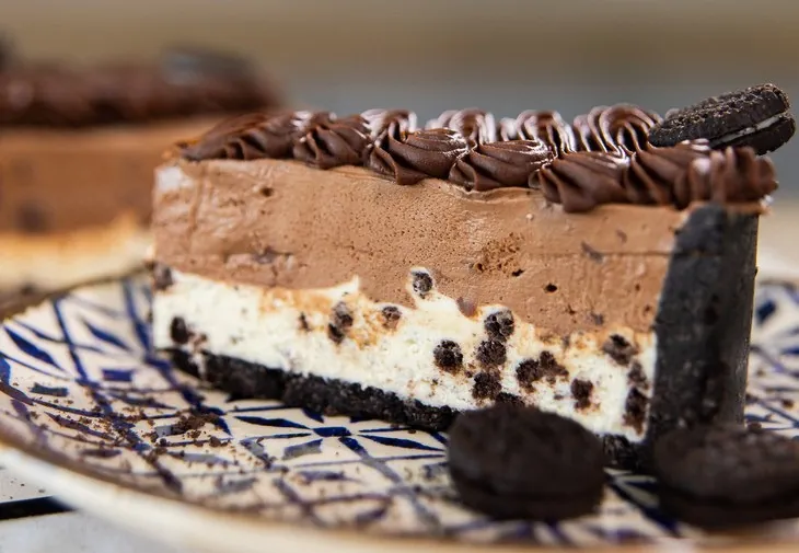 Fatia da torta de Oreo com mousse de chocolate e biscoitos decorando